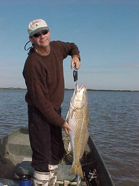 Joe shows off his beautiful 22 lb. redfish caught on the shore of the lake.